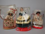 three dolls in plastic bags sitting on a table next to each other