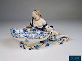une figurine ancienne en porcelaine représentant une femme assise à l'avant d'un bateau