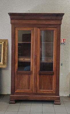 a wooden cabinet with a glass door and a painting on the wall