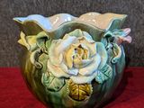 un vase vert orné d'une rose blanche, posé sur un tissu rouge
