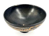 a black bowl with gold designs on it on a white surface