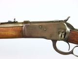 a close up of a rifle with a wooden handle on a white background