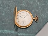 une montre de poche en or posée sur une surface en marbre