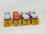 four toy cars are lined up on boxes on a white surface