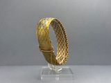 a close up of a gold bracelet on a clear stand