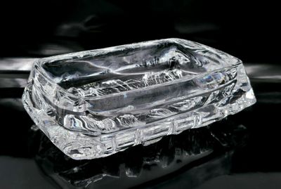 un cendrier en verre transparent posé sur une surface noire