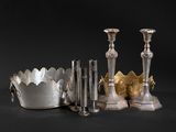 several silver candlesticks and a silver bowl on a black background