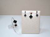 silver and black flower earrings and ring on a white display case