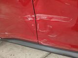 a close up of a red car that has been dented