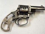 un revolver argenté posé sur une surface blanche, avec une crosse noire