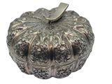 a silver pumpkin shaped box on a white surface