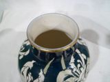 un vase bleu et blanc à bord doré posé sur une table