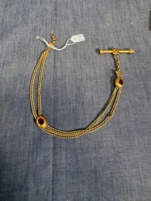 un gros plan d'un bracelet en or orné d'une pierre rouge