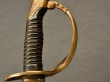 a close up of a sword with a gold handle on a black background