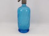 a blue glass bottle with a metal spout on a white surface