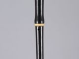 a black and gold flute with a wooden handle on a white surface