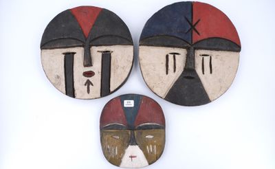 Trois masques africains sont exposés sur un fond blanc