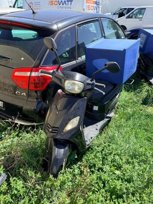 une voiture garée à côté d'un scooter dans l'herbe