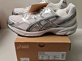 deux paires de chaussures de course Asics posées sur une boîte, elle-même posée sur une table