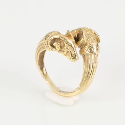 a close up of a gold ring with two rams on it