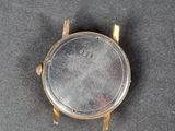 a close up of a gold watch on a black surface