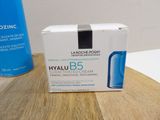 a box of hydrating cream sitting on a table next to a bottle of water