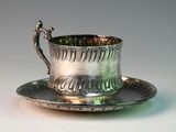 a silver cup and saucer sitting on a saucer