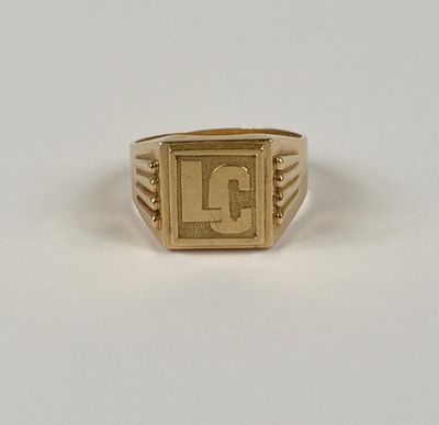 un gros plan d'une bague en or sur laquelle figure la lettre « l »