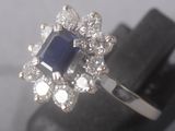 a close up of a diamond and sapphire ring on a stand