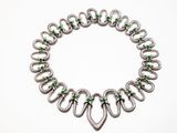 un gros plan sur un bracelet en argent orné de pierres vertes
