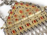 silver and gold necklace with red stones and chains on a white surface