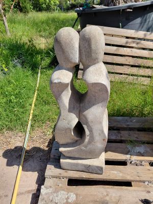 une sculpture en pierre représentant un couple assis sur un banc en bois