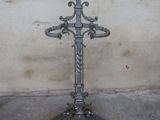 a metal cross on a stand in front of a wall