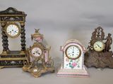 four different clocks sitting on a table with a white background