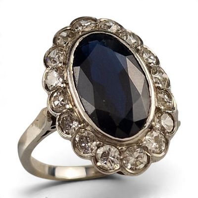 une image représentant une bague ornée d'une grosse pierre noire entourée de petits diamants blancs