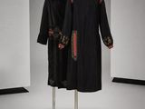 deux robes noires et rouges posées sur un portant dans une pièce