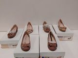 Quatre paires de chaussures sont exposées dans une boîte blanche