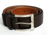 ceinture en cuir marron avec une boucle argentée sur un fond blanc