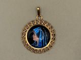 a close up of a gold plated pendant with a picture of a woman in a blue dress