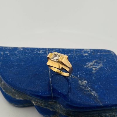 a close up of a gold ring with a diamond on top of a blue stone