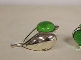 pair of silver and green glass bird earrings on a white surface