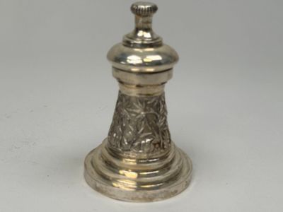 un petit bougeoir en argent posé sur une table blanche