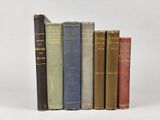 six vieux livres sont alignés sur une surface blanche