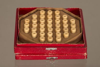 une boîte rouge contenant un tas de perles en bois