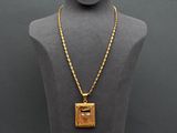 a gold necklace with a square pendant on a mannequin