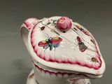 a close up of a white and pink teapot with a butterfly on it