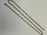 un collier en or muni d'une chaîne, posé sur une surface blanche