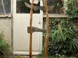 une sculpture représentant deux haches posées sur un socle en bois devant un bâtiment