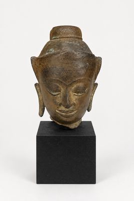 une image représentant une tête de Bouddha en bronze posée sur un socle noir