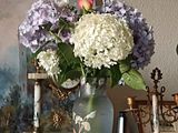 a vase of flowers sitting on a table next to a painting